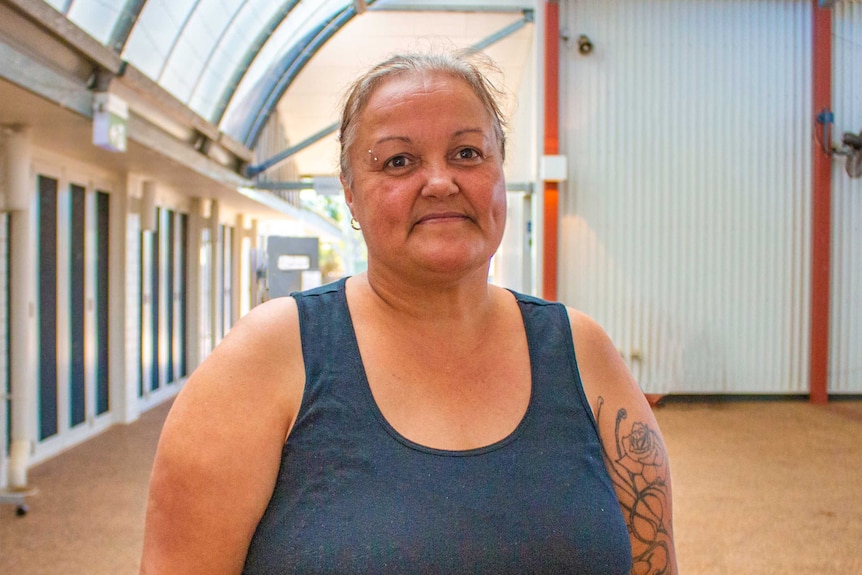 A woman wearing a singlet stands in an empty building.