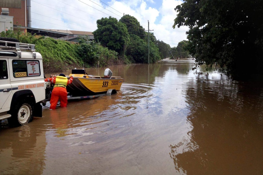 An SES volunteer unloads a boat into floodwaters in Maryborough.
