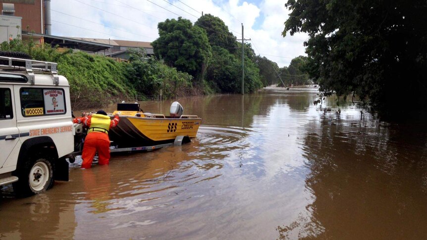 An SES volunteer unloads a boat into floodwaters in Maryborough.