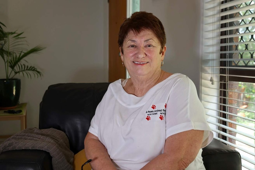 A woman sitting smiling on a seat inside a house.