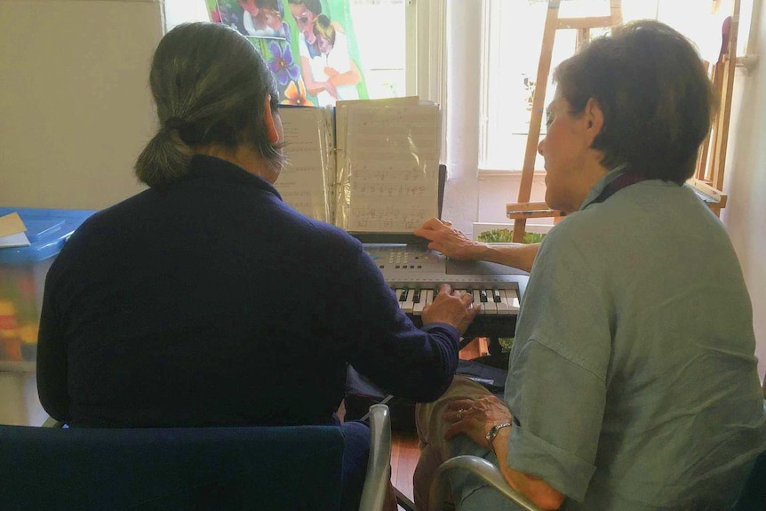 Two women sit at a piano