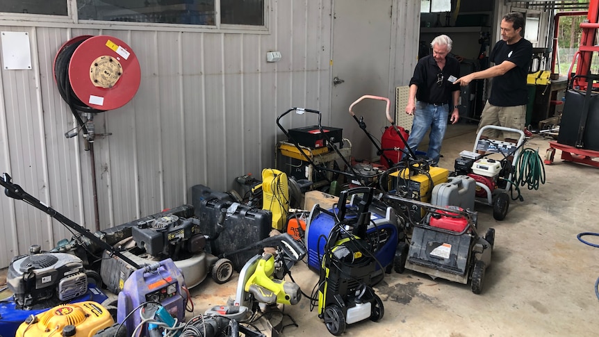 Two men looking at a pile of flooded tools.