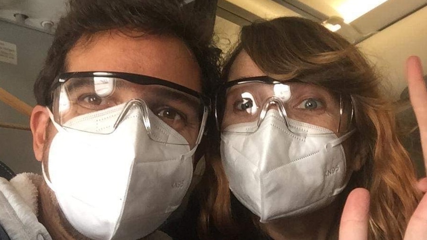A couple wear face masks as they board a plane from Mexico to Australia