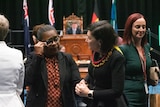 two women, one wiping away tears, standing in Queensland parliament