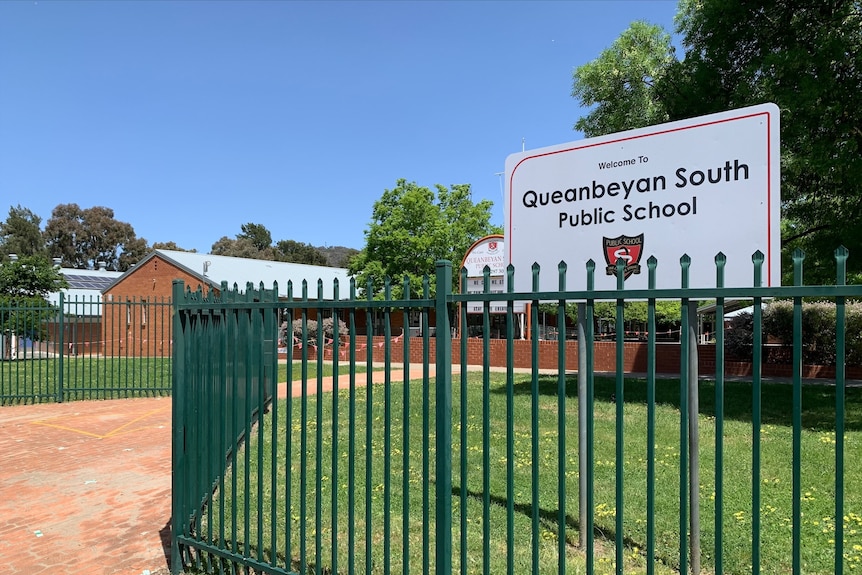 A sign outside a school that reads 'Queanbeyan South Public School".