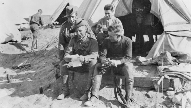 Group of WWI soldiers reading a letter outside their tent