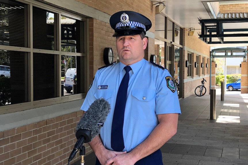 A policeman in his uniform addressing the media in front of Wollongong Police Station.