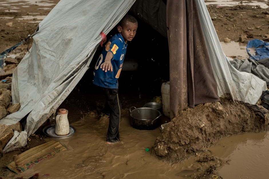 A child inside a tent, which has flooded in the rain.