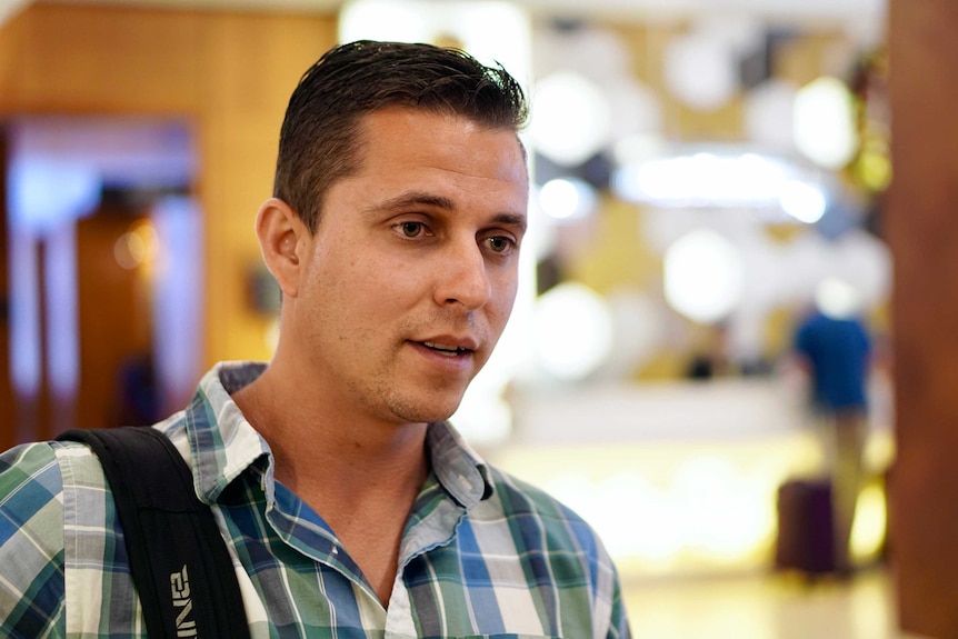 Marco Da Silva wearing a blue and green shirt, speaks to a journalist.