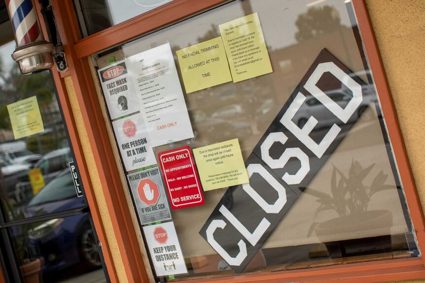 A barber shop in California with a large CLOSED sign in the window.