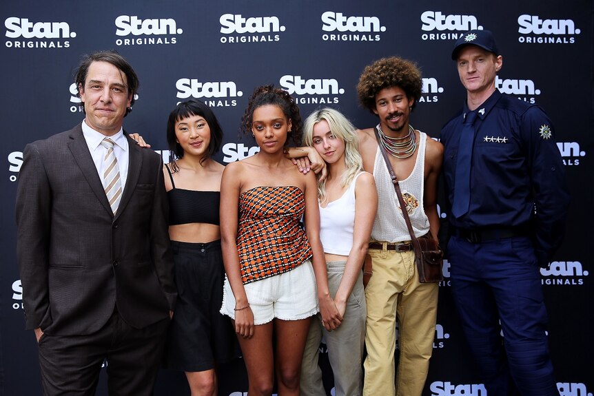 Six people standing in front of a post with 'Stan originals'