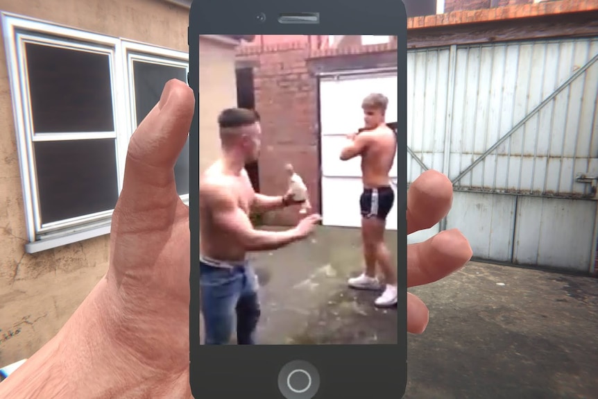 A computer game hand holding a phone with the image of two shirtless men about to fight