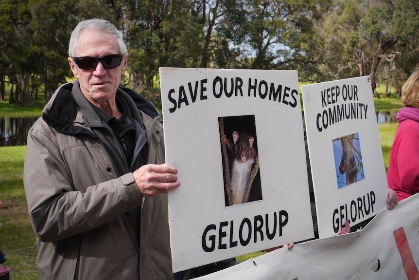 A man holding two signs in a rural setting