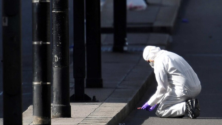 A police forensics investigator wearing a white disposable suit works on London Bridge after the attack.
