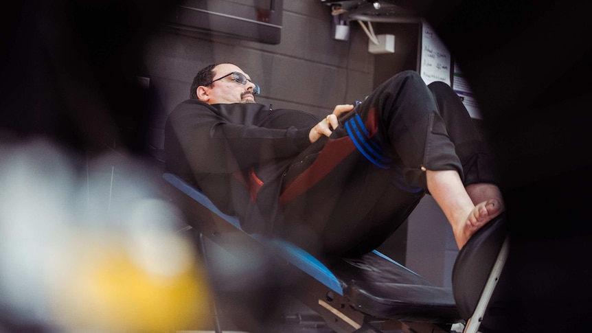 A man on a leg weight machine in a gym.