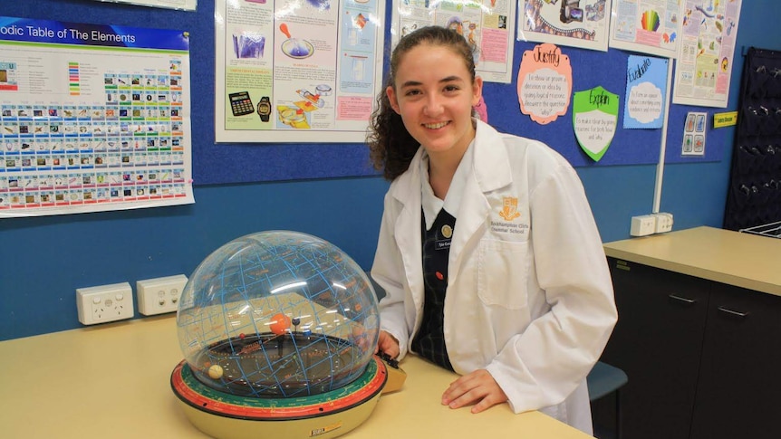 Year 11 student Tylar Cunzolo in lab coat with a model of the solar system