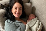 Woman laying down on the couch while holding her baby in her arms 