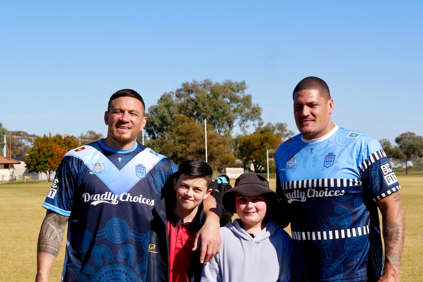 Sonny Bill Williams and Willie Mason pose for a photo with two young male children. 