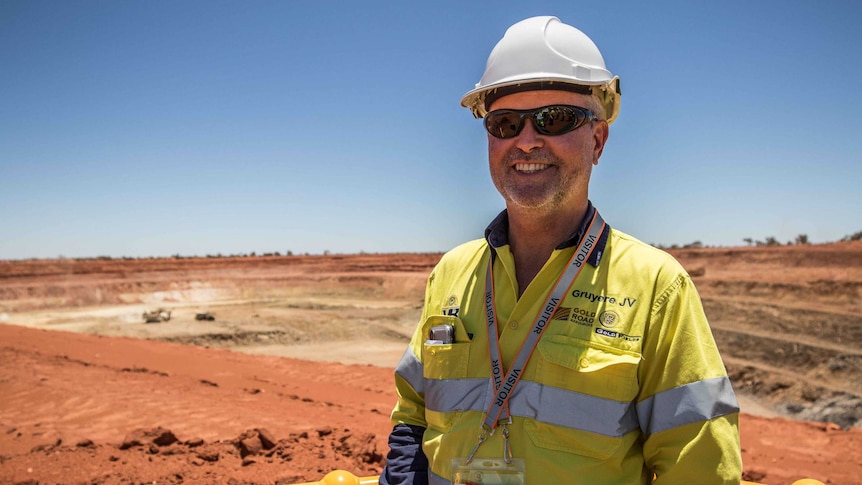 Miner in front of open mine pit