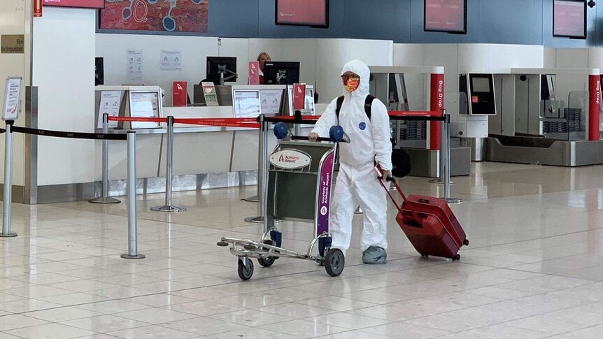 A person wearing a white protective suit walking in Adelaide Airport