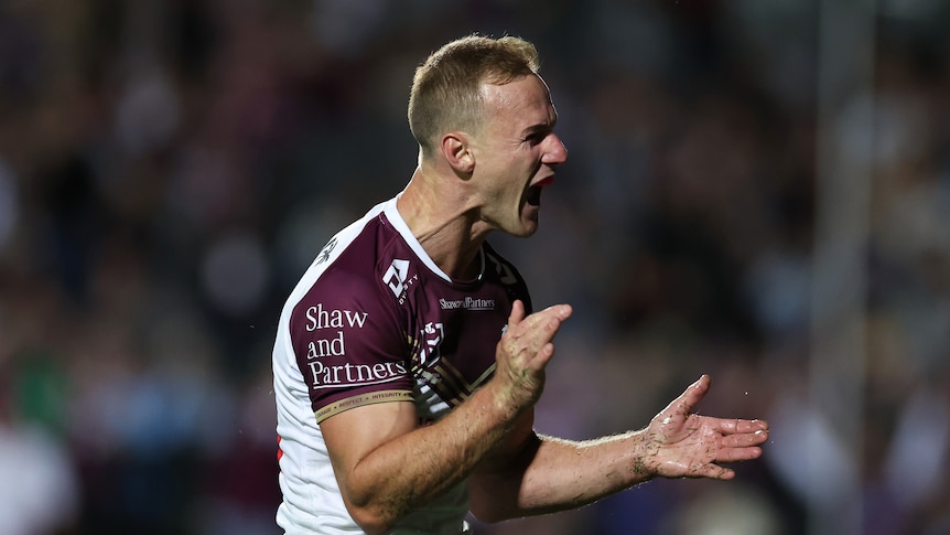 A man celebrates after scoring a try in an NRL match
