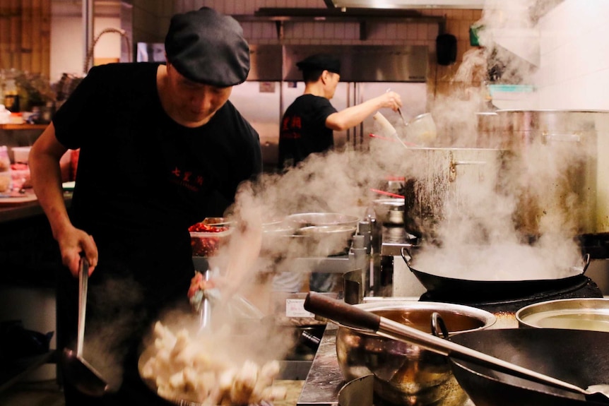 Chefs cooking in the kitchen of a Chinese restaurant.