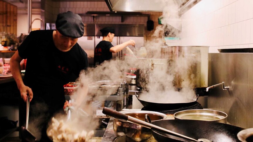 Chefs cooking in the kitchen of a Chinese restaurant.