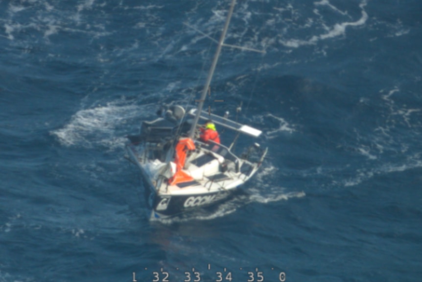 A boat in the middle of the ocean with a figure in orange high-vis gear