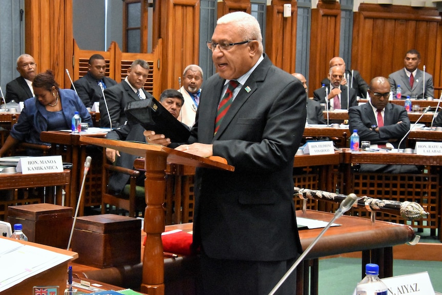 Frank Bainimarama 在议会中拿着一本圣经。