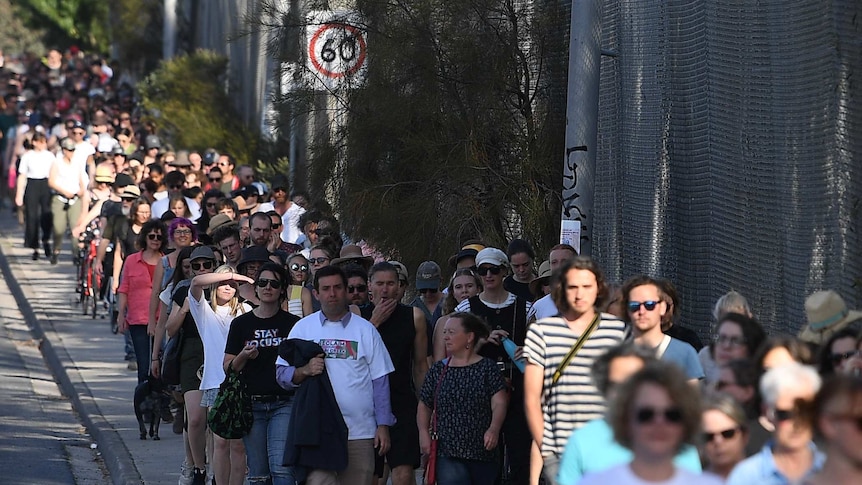 A group of hundreds walk along a footpath.