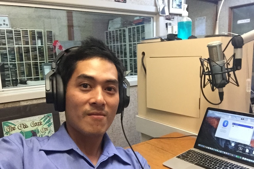 A man taking a selfie in a radio booth, wearing headphones.