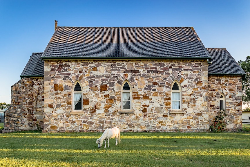 Small stone church with a pony out front.