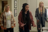 Three teenage girls stand in a room