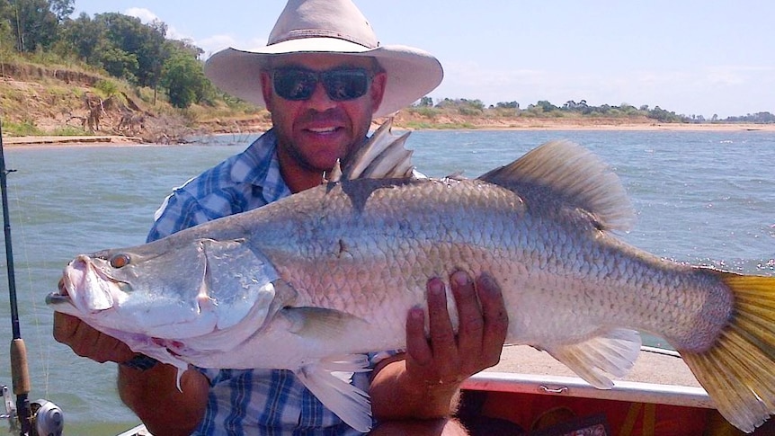 Andrew Symonds on a boat holding a large fish.