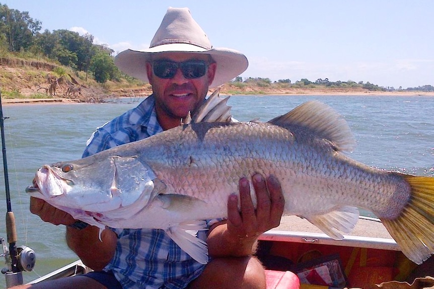 Andrew Symonds on a boat holding a large fish.