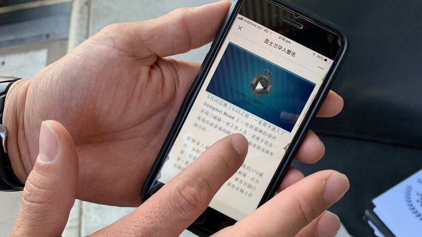 A hand holds an iPhone displaying the Queensland Police supported WeChat account.