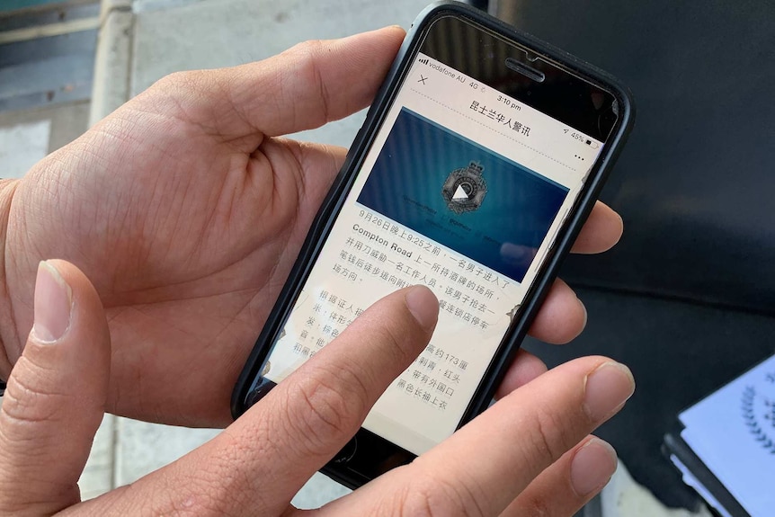 A hand holds an iPhone displaying the Queensland Police supported WeChat account.