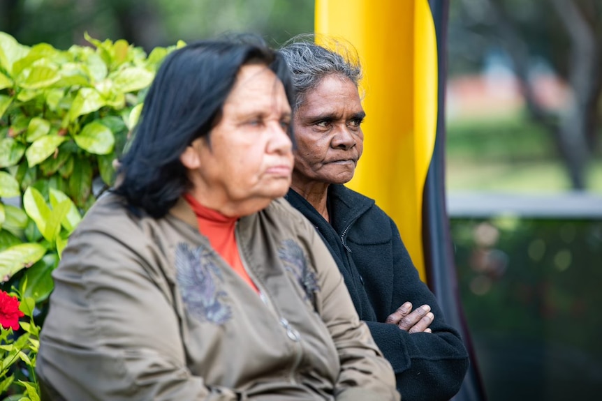 Maria Williams sitting and looking serious with Noelene in the foreground. 