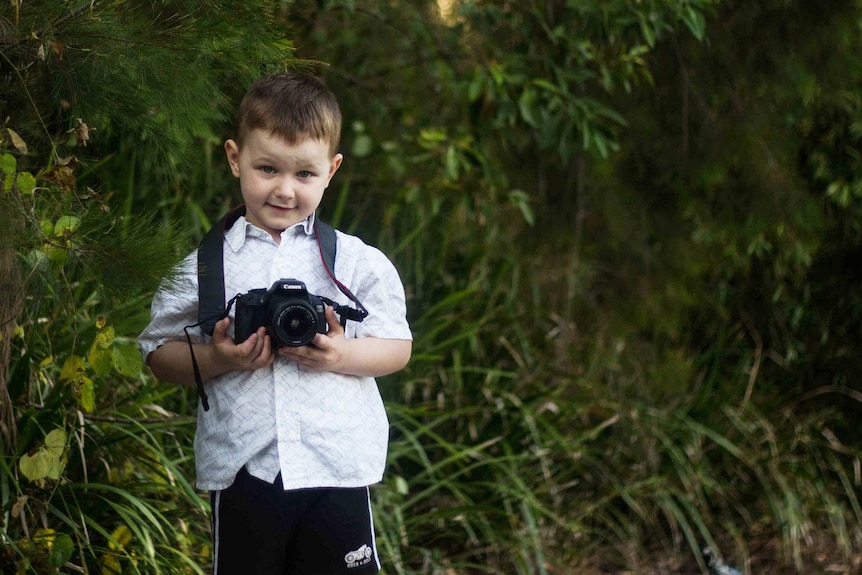 Max, 4, holding a camera in his hands