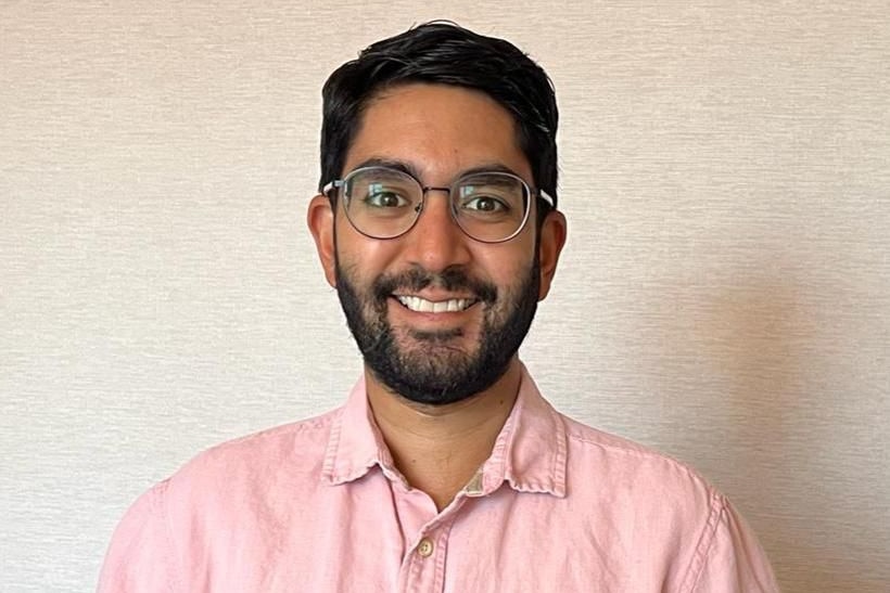 A man smiling in pink shirt and glasses 