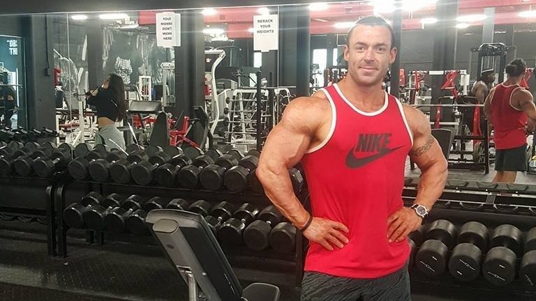 A man in a red singlet standing in a gym