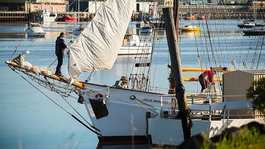 Julie Burgess tied up in Devonport, a crewman standing on her bowsprit