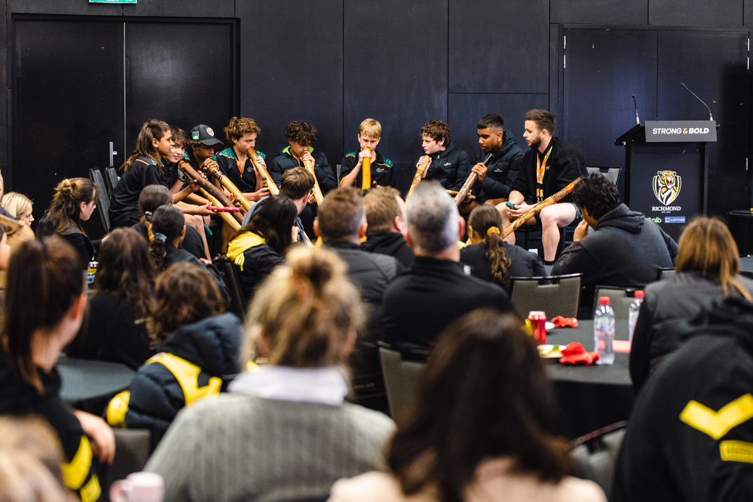 the Yidaki Boys group playing didjeridus on stage at richmond football club