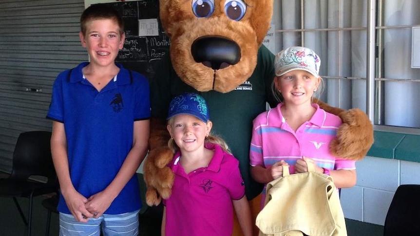 Wallaby mascot wearing a fire hat standing with three children