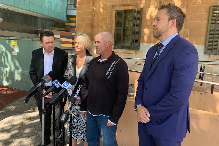 Four people stand in a line for a political announcement.