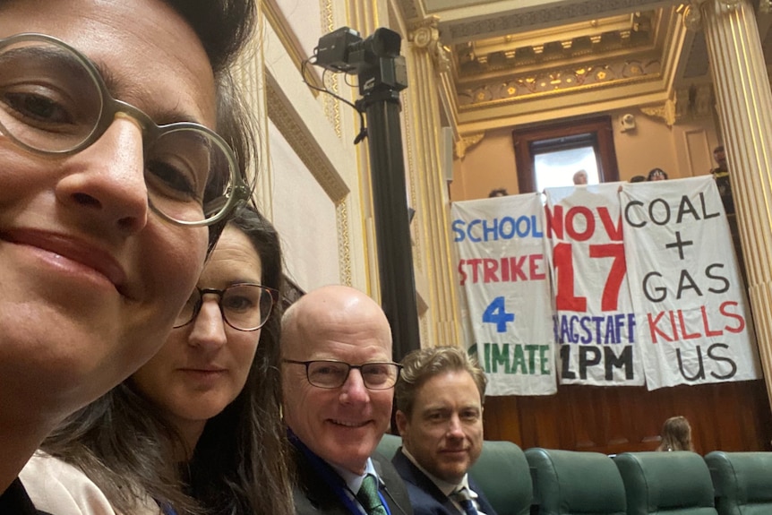 Gabrielle de Vietri and three of her colleagues sitting in the lower house, behind them are three climate change banners.