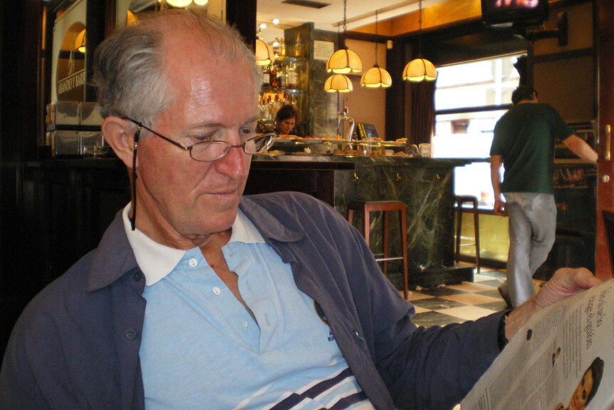 Clive Deverall reads a newspaper in a cafe