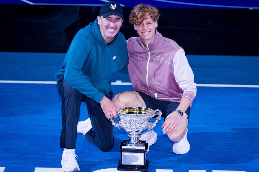 Darren Cahill and Jannik Sinner pose with the Australian Open trophy.