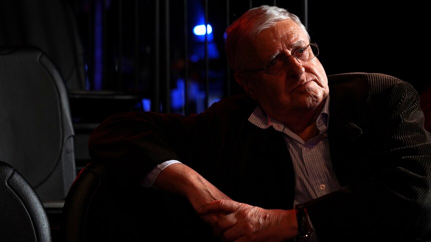 Portrait of a 79-year-old man sitting in a dark theatre on seat