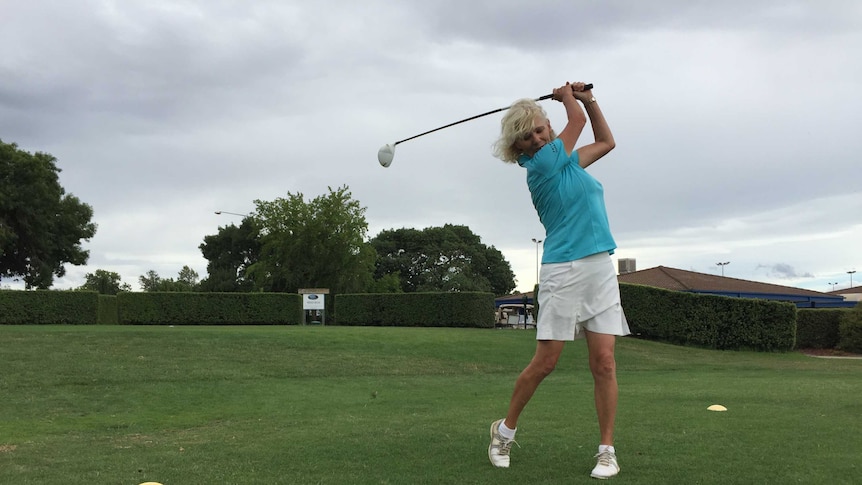 A woman swings a golf club.